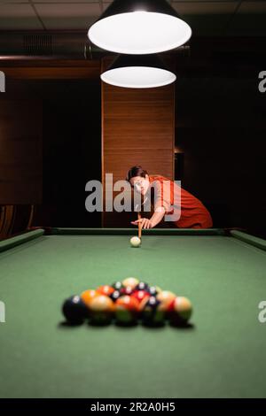 Belle jeune femme sur le point de briser la pyramide de balles dans le billard sur le billard de snooker Banque D'Images