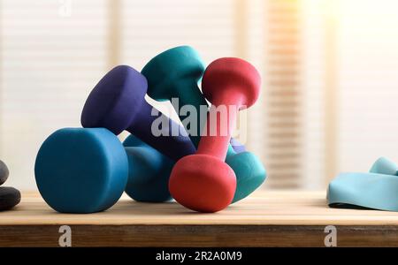 Arrière-plan sportif avec planche en bois avec haltères et arrière-plan avec fenêtre. Vue avant. Banque D'Images