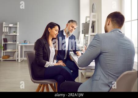 Homme et femme en discussion avec un agent immobilier, un directeur de banque ou un courtier en prêts Banque D'Images