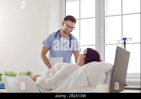 Une infirmière sympathique donne la ligne IV à une patiente qui est allongée sur un lit médical à la clinique Banque D'Images