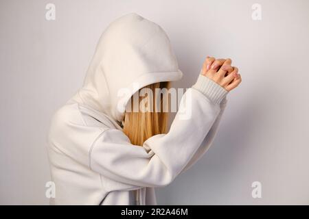 Jeune belle fille dans un blanc à capuchon posant. Pull à capuche ultra-large chaud avec capuche. Noeud tendance. Essayer de porter des vêtements en magasin. Sous-culture de la jeunesse Banque D'Images