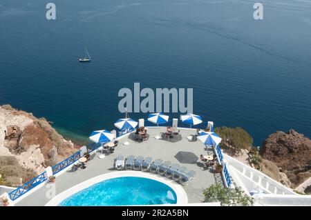 Une terrasse avec piscine, chaises longues et coin salon offre une vue panoramique imprenable sur la caldeira et la mer de Santorin. Idéal pour des vacances de détente s Banque D'Images