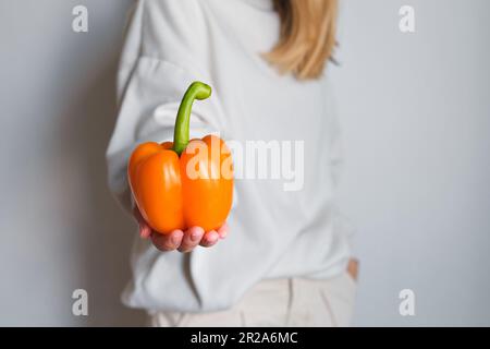 La fille tient le poivron de couleur dans ses mains. Poivre doux, frais et mûr. Aliments sains, légumes biologiques. Vitamines naturelles, ingrédient brut Banque D'Images