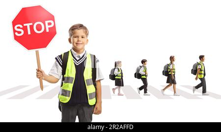 Garçon d'école avec gilet réfléchissant tenant un panneau d'arrêt et enfants traversant la rue au passage piéton isolé sur fond blanc Banque D'Images