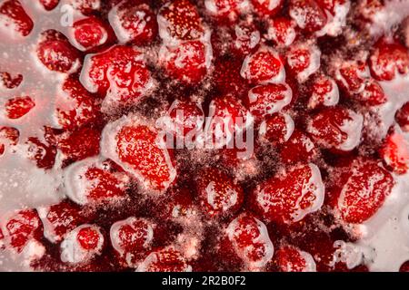 Processus de fabrication de confiture de framboises maison. Sirop doux rouge bouillant sur la cuisinière de près. La confiture de fraises a l'air très appétissante. Confiture de fraises maison bouillante. Faire une confiture de fraises. Banque D'Images