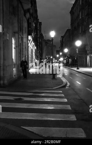 Une vue sur la rue avec une route étroite la nuit avec des nuages sombres en arrière-plan à Gijon, en Espagne. Banque D'Images