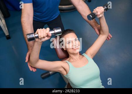 Gaie femme athlétique mature faisant l'exercice du haut du corps avec des poids Banque D'Images
