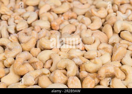 Gros plan sur les noix de cajou salées délicieuses dans un cadre culinaire. Anacardium occidentale. Noix de cajou grillées en forme de haricot brun clair avec cristaux de sel blancs. Banque D'Images