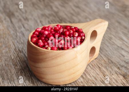 Tasse avec de savoureuses baies de lingonis mûres sur table en bois, en gros plan Banque D'Images