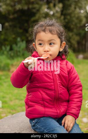 manger délicieuse gelée latine fille avec les cheveux recueillis vêtements décontractés, ustensiles de cuisine, appréciant le dessert doux, style de vie et portrait Banque D'Images