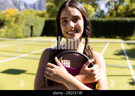 Portrait d'une femme caucasienne en bonne forme tenant une raquette de tennis sur un court de tennis extérieur ensoleillé Banque D'Images
