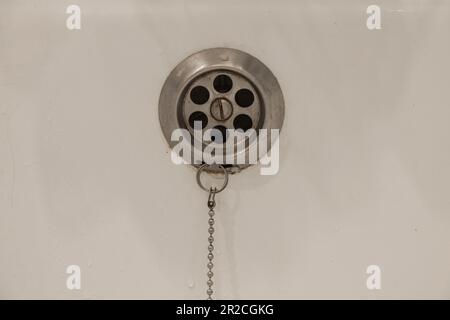 Eau de drainage avec bouchon en caoutchouc de drainage sur la baignoire de douche blanche de près Banque D'Images