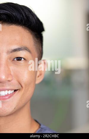 Demi-portrait d'un homme asiatique heureux et inaltérés qui regarde l'appareil photo et sourit à l'hôpital Banque D'Images