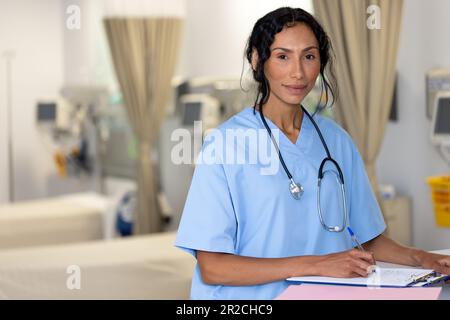 Portrait non modifié d'une femme biraciale souriante médecin portant un stéthoscope à la réception de l'hôpital Banque D'Images