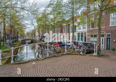 Delft, pays-Bas - 26 avril 2023 : ancien canal de Delft au printemps avec des bâtiments à vélo et au bord de l'eau et des arbres verts Banque D'Images