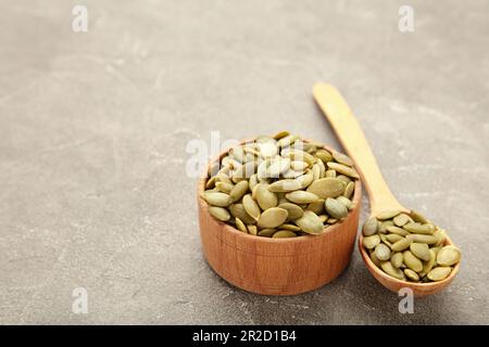 Graines de citrouille dans un bol en bambou et cuillère sur le gris. Vue de dessus Banque D'Images