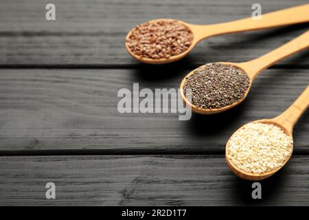 Aliments de grande qualité : sésame, graines de tournesol, graines de lin et chia sur le noir. Graines sur cuillère vue de dessus. Banque D'Images