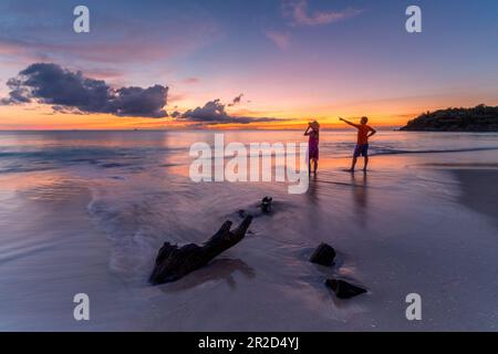 Homme et femme admirant le coucher du soleil sur la plage tropicale, Caraïbes Banque D'Images