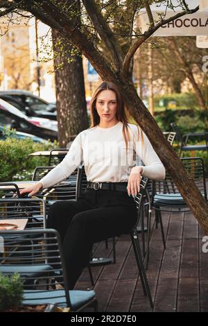 Les beaux escaliers blancs de fille sur vous tout en étant assis dans la caffe Banque D'Images