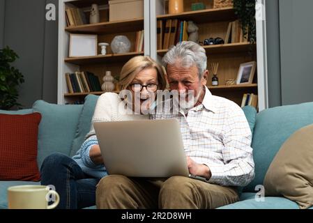 Couple senior excité surpris par de bonnes nouvelles, incroyable victoire inattendue, énorme centre commercial offre de vente sur le site web, étonné d'âge moyen plus fa Banque D'Images