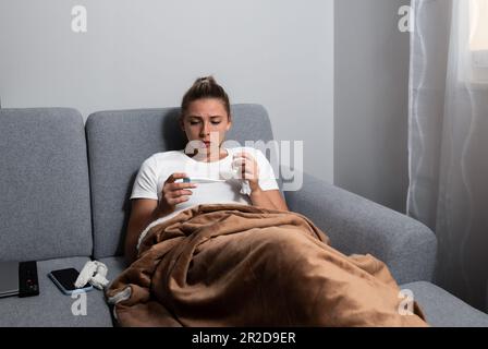 Grippe. Femme attrapée par le froid. Éternuer dans les tissus. Maux de tête. La médecine du virus. Jeune femme infectée par le froid soufflant son nez à Handkerchief. Femme malade W Banque D'Images