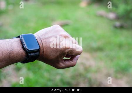 Montre noire et bracelet sur le poignet gauche des hommes, espace de rédaction sur la droite pour la saisie de texte. Il s'agit d'une photo de gros plan avec un arrière-plan flou. Banque D'Images