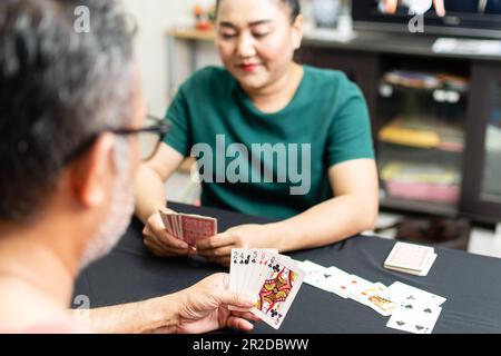 Couples jouant aux cartes à la maison pour la nuit de la date à l'intérieur. Ils ont tous les deux tenu des cartes dans leurs mains et sourit joyeusement. Le concept pour un jeu sur, l'amour, profiter, h Banque D'Images