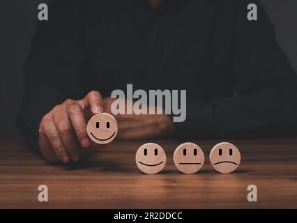 un homme de service client meilleure expérience d'évaluation d'entreprise excellente. Concept d'enquête de satisfaction. La main de l'homme d'affaires choisit un visage souriant sur un Banque D'Images