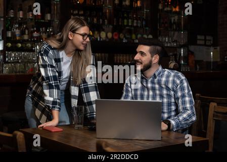 Les hipsters millénaires mari et femme propriétaires de café bar restaurant assis dans la soirée après la clôture de parler de vérification des bénéfices, ventes calcul ORD Banque D'Images