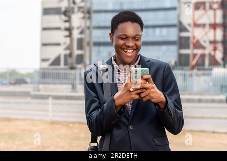 un jeune homme africain regarde le téléphone et semble surpris Banque D'Images