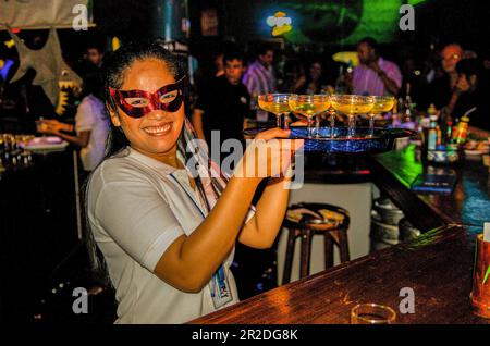 La serveuse masquée sert du champagne à des clients assoiffés à minuit pendant la fête de la Saint-Sylvestre, Sharky Bar, Phnom Penh, Cambodge. © Kraig Lieb Banque D'Images