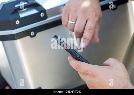 Mains d'un homme tenant un mobile et le touchant avec ses doigts où vous pouvez voir un anneau de mariage Banque D'Images