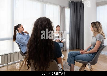 Entraîneure, thérapeute ou chef d'équipe d'affaires souriante et heureuse, aidant et motivant les jeunes femmes à une séance de thérapie de groupe ou à une séance d'entreprise Banque D'Images