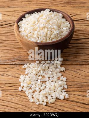 Canjica séché, maïs hominy ou blanc sur un bol sur une table en bois. Banque D'Images