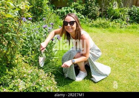 Une jeune femme de 30s ans qui a tendance à avoir un petit jardin urbain au soleil de printemps Banque D'Images