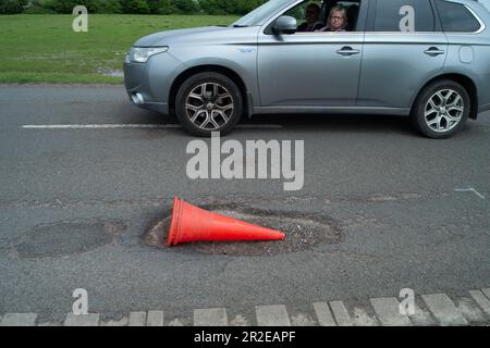 Dorney, Buckinghamshire, Royaume-Uni. 19th mai 2023. Bien que certains nids-de-poule soient aujourd'hui parés dans le village rural voisin de Dorney Reach dans Buckinghamshire, il reste encore un certain nombre de nids-de-poule sur la route commune dans Dorney Village qui ont encore besoin de réparation. Celui-ci est doté d'un cône d'avertissement, mais il est constamment renversé par le trafic qui passe. Buckinghamshire a des milliers de nids-de-poule non réparés qui sont lentement mis en place à l'aide d'une nouvelle machine Velocity Patcher. Crédit : Maureen McLean/Alay Live News Banque D'Images