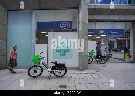 Londres, Royaume-Uni. 19 mai 2023 Une promenade piétonne à côté de Lime location de vélos électriques abandonnés à l'extérieur d'un magasin de pharmacie Boots dans la rue Victoria. Les compagnies de location de vélos électriques telles que Lime by Uber, Human Forest, et dott, n'ont pas de places de stationnement contrairement à Santander. Le Conseil de Westminster élabore des plans pour les cavaliers qui ne parcoutent pas correctement leurs cycles loués laissés sur des trottoirs qui peuvent poser une obstruction aux piétons et aux utilisateurs de fauteuils roulants. Credit: amer ghazzal / Alamy Live News Banque D'Images