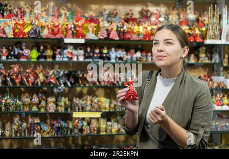 Happy female touriste choisit des souvenirs artisanaux espagnols - des figurines de danseurs de flamenco exposées dans la boutique pour la vente Banque D'Images