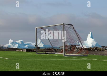 Terrain de soccer au bord de la mer; à la périphérie de Qeqertarsuaq; île Disko dans l'ouest du Groenland; Icebergs flottant au large de la côte encadrent le but du soccer; Banque D'Images