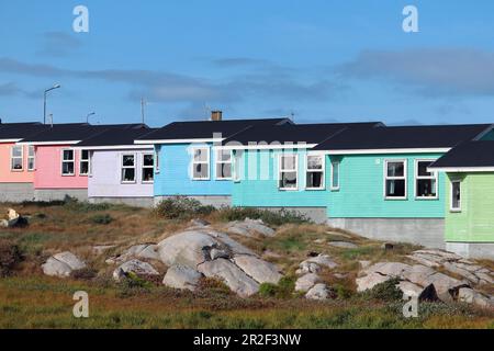 Maisons colorées en bois de couleur arc-en-ciel; Qeqertarsuaq sur l'île Disko, dans l'ouest du Groenland; en premier plan, collines herbeuses et terrain partiellement rocheux; Banque D'Images