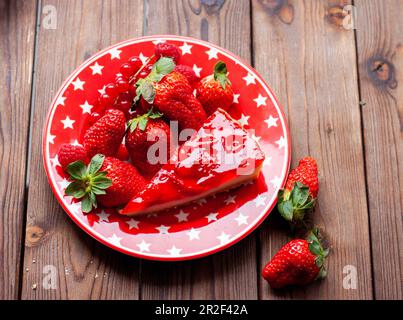 Morceau de gâteau au fromage de fraise avec fraisier frais pour l'anniversaire sur fond de bois rustique Banque D'Images