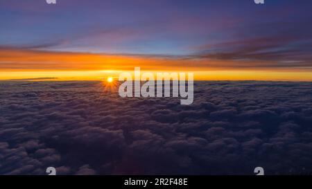 Coucher de soleil sur une couverture nuageuse fermée, vue aérienne depuis le cockpit d'un avion de ligne Banque D'Images