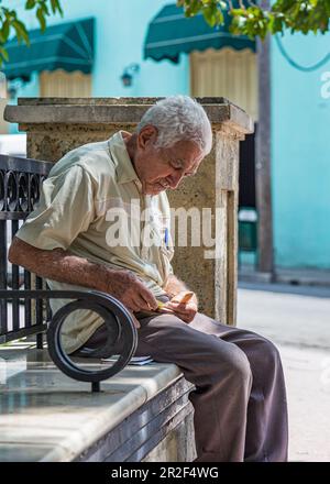 Homme cubain âgé assis sur un banc de parc, Camagüey, Cuba Banque D'Images