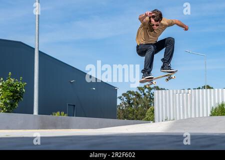 Skateboarder faisant le tour de l'ollie sur une scène urbaine. Banque D'Images