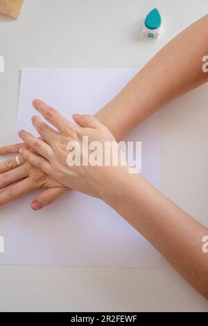 Vue de dessus des mains d'une femme appuyant sur un tampon en caoutchouc sur une feuille de papier vierge Banque D'Images