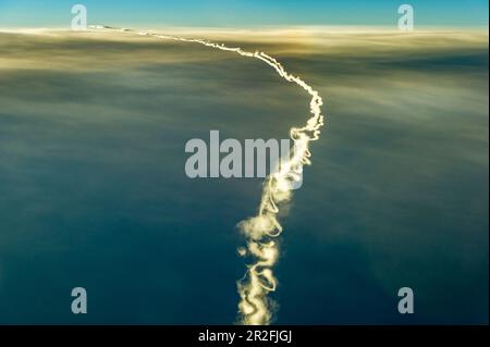 Avion avec long, fin et tourbillonnant contrail sur la couche de nuage dans un virage à gauche Banque D'Images