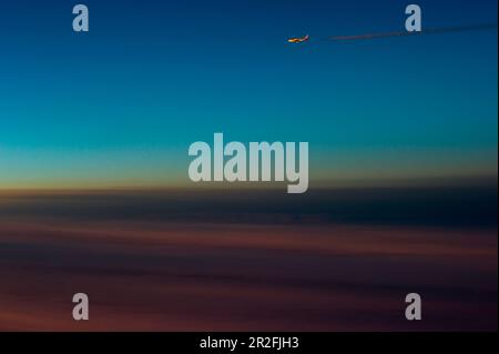 Avion avec contrailles au crépuscule Banque D'Images