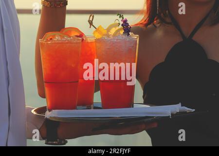 Un serveur tient un plateau de cocktails, de cocktails, de cocktails et de boissons rafraîchissantes au bar sur le toit Banque D'Images