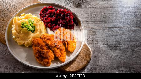 Escalopes de poulet panées servies avec des pommes de terre et des betteraves Banque D'Images