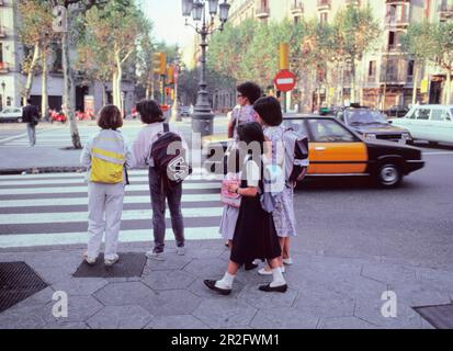 Barcelone Espagne Catalogne écoliers avec sacs à dos. Des écolières qui vont à l'école. Enfants à un croisement zèbre au coin de la rue trottoir. Banque D'Images